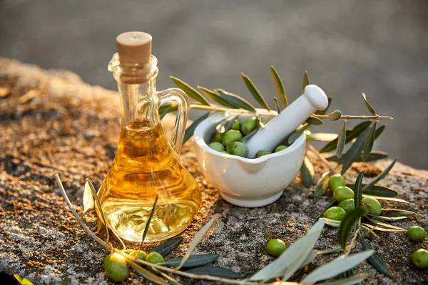 jug with olive oil and green olives on table