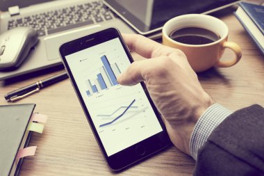 Erkek eli modern akıllı telefon kullanıyor. Ekranda grafik var. İş konsepti. 