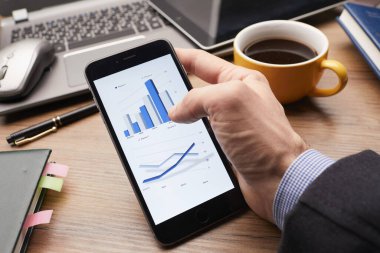 Erkek eli modern akıllı telefon kullanıyor. Ekranda grafik var. İş konsepti. 