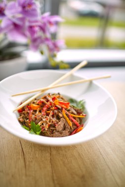 Kızarmış erişteli sobayı sığır eti ve çubukla karıştırın, yakından bakın.