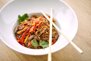 Kızarmış erişteli sobayı sığır eti ve çubukla karıştırın, yakından bakın.