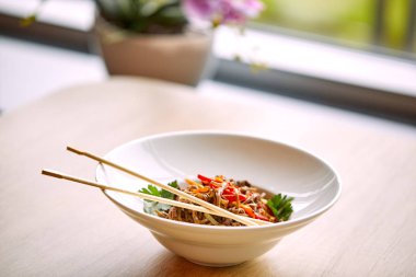 Kızarmış erişteli sobayı sığır eti ve çubukla karıştırın, yakından bakın.