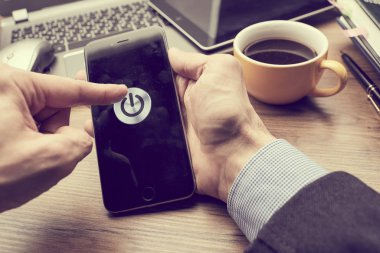 Erkek eller modern akıllı telefonu tutuyor. Ekranda güç düğmesi var. İş kavramı. 