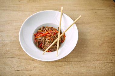 Kızarmış erişteli sobayı sığır eti ve çubukla karıştırın, yakından bakın.