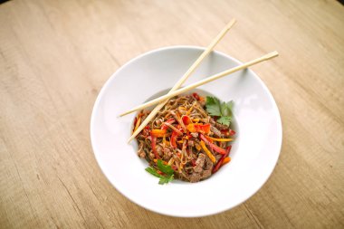 Kızarmış erişteli sobayı sığır eti ve çubukla karıştırın, yakından bakın.