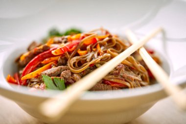 Kızarmış erişteli sobayı sığır eti ve çubukla karıştırın, yakından bakın.