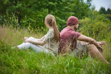 güneşli bir günde ormana yakın çayırda oturan iki gezgin 