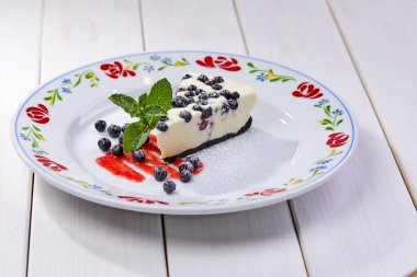 Taze yaban mersinli cheesecake ve beyaz tabakta nane şekeri, yakın görüş.