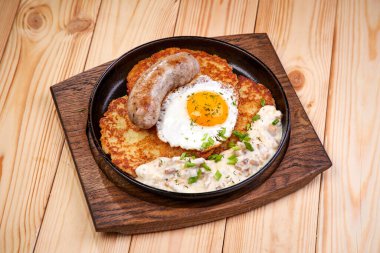 Patates krepli tava ve ahşap kesme tahtasının üzerinde sosisli yumurta, yakın görüş. 