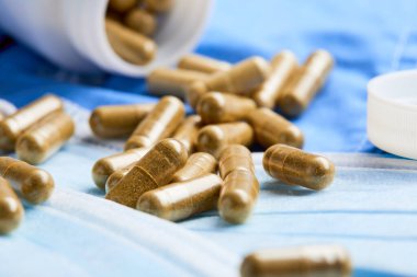 İlaç kapsülleri ve tıbbi maskeler mavi arka planda. Tıp konsepti. Coronavirüs