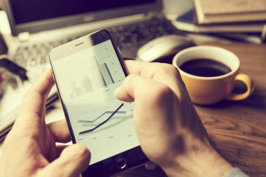 Erkek eller modern akıllı telefon kullanıyor. Ekranda grafik var. İş konsepti. 