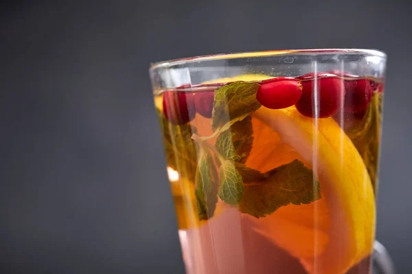 winter drink with herbs and fruits in glass, close view