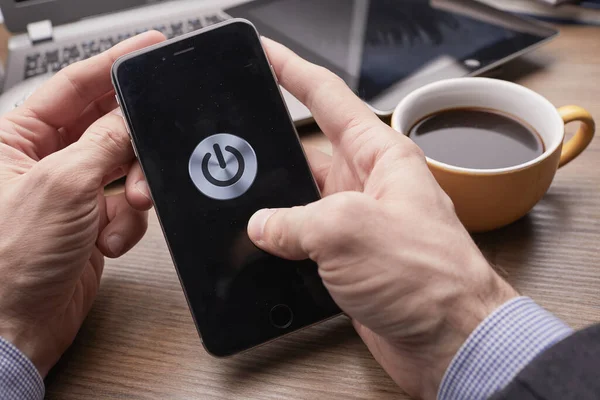Erkek eller modern akıllı telefonu tutuyor. Ekranda güç düğmesi var. İş kavramı. 