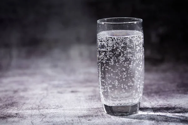 Glass of sparkling water on grey background