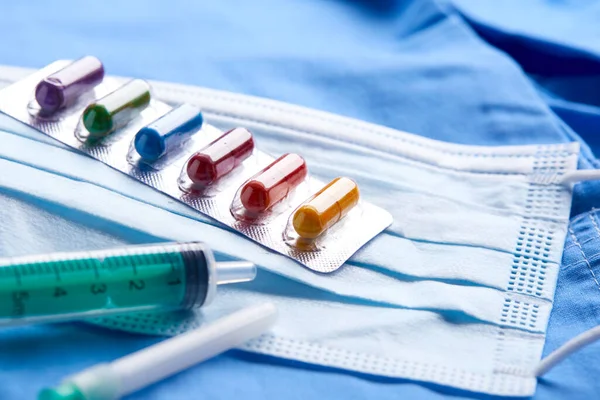 青の背景にカプセルと医薬品の注射器や医療用マスク 医学の概念 コロナウイルス — ストック写真