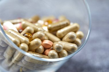 ilaç hapları ve kapsüller gri yüzeyde camda