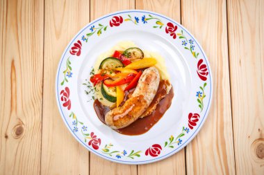 Izgara sebzeli sosis ve beyaz tabakta sos, yakın görüş. 