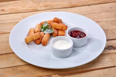 Beyaz tabakta soslu krem peynir çubukları, yakın görüş. 