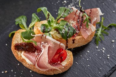 Karanlık tahtada etli ve sebzeli kanepeler, yakın görüş.