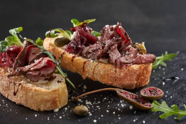 Karanlık tahtada etli ve sebzeli kanepeler, yakın görüş.