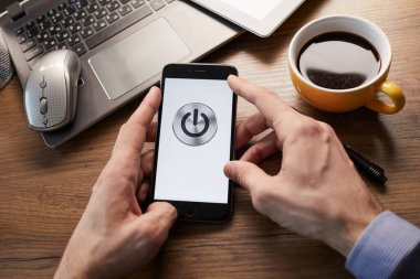 Erkek eller modern akıllı telefonu tutuyor. Ekranda güç düğmesi var. İş kavramı. 