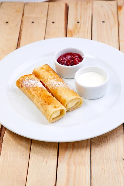 stuffed pancakes with cream cheese on white plate, close view