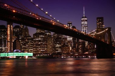 Gece vakti Brooklyn Köprüsü ve Manhattan Skyline 'ın görüntüsü, Empire Fulton Ferry Park' tan görüldü..