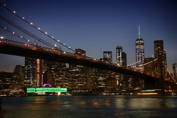 View of night scene of the Brooklyn bridge and Manhattan Skyline at Night, seen from Empire Fulton Ferry Park.