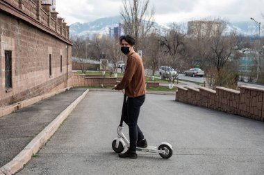 Genç adam şehirde scooter kullanıyor.