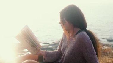 Bir Asyalı kadın ve deniz manzaralı bir kitap.