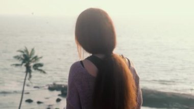 Çekici Asyalı kadın, deniz manzaralı dağın kenarında oturmuş kitap okuyor. Genel plan