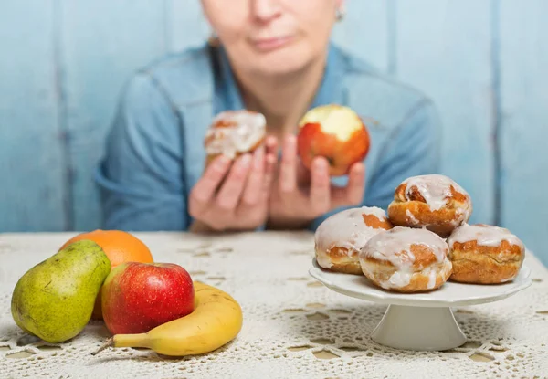 Woman choosing between fruit and sweets — Stock Photo, Image