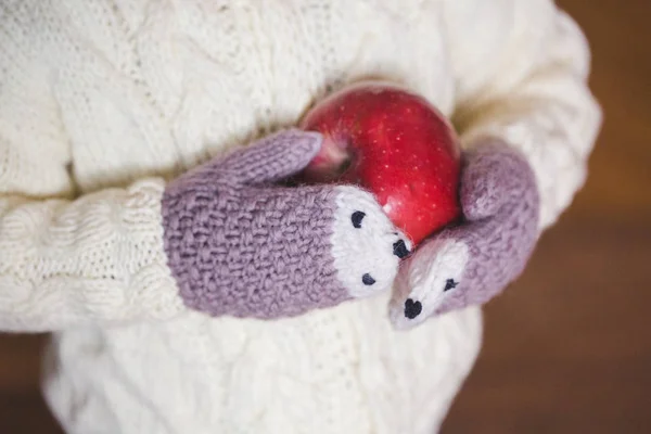 Kids hands in cozy mittens holding red apple — Stock Photo, Image