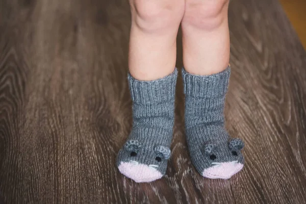 Baby fötter på vintern mus strumpor på trägolvet — Stockfoto