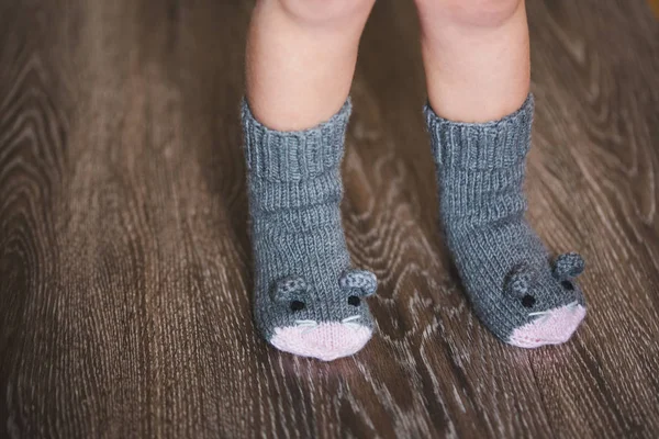 Baby fötter på vintern mus strumpor på trägolvet — Stockfoto