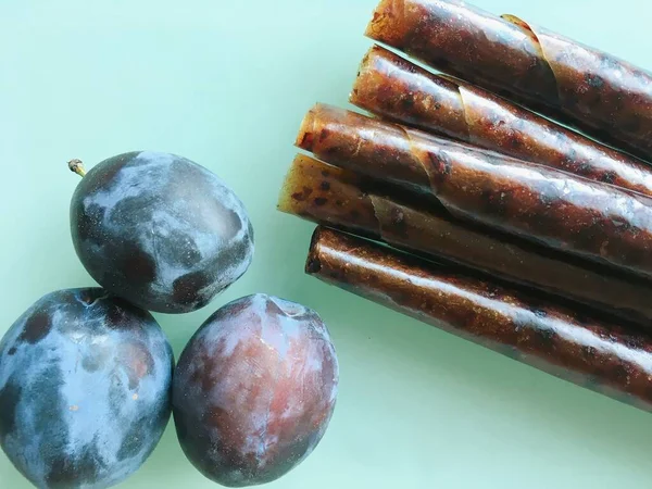 Sweet pureed fruit pastille. Fruit roll-ups homemade on a wooden background. Natural sweets from plum fruits.