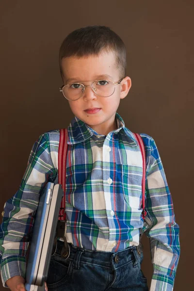 Ritratto di un ragazzo carino e serio che usa un portatile. Bambino in occhiali con un computer portatile — Foto Stock