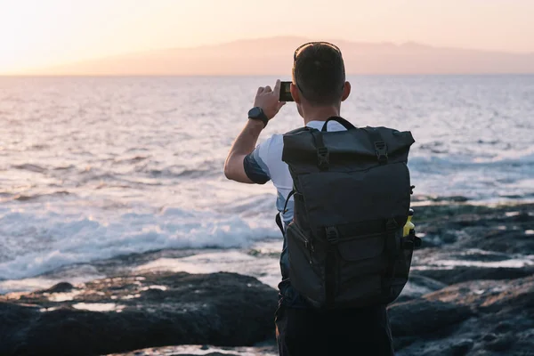 Homme prenant des photos du coucher du soleil avec téléphone portable — Photo