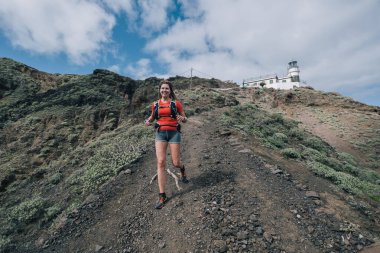 Ülke genelinde koşan spor koşucusu kadın. Formda kadın koşucu egzersizi yapıyor ve güzel dağ manzarasında dışarı zıplıyor.