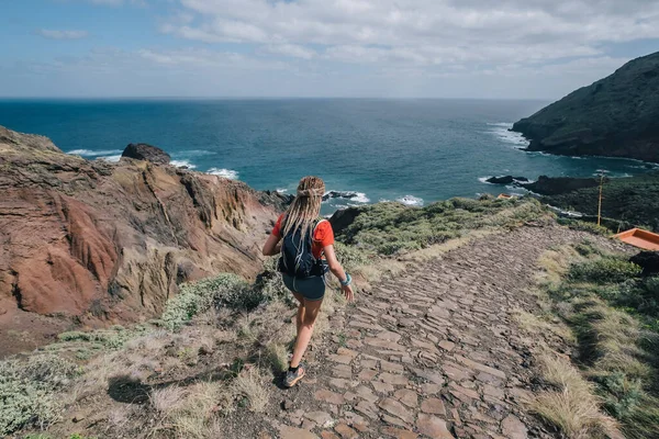 Mujer corre a través del país en un camino de montaña en la isla de Canarias. Vista al mar —  Fotos de Stock
