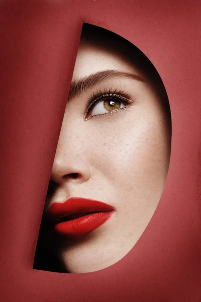 Kvinna ansikte Titta igenom rött eller turkos trasig kartong som skönhet begrepp med copyspace — Stockfoto