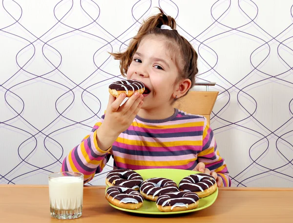 Liten flicka äter choklad donuts — Stockfoto