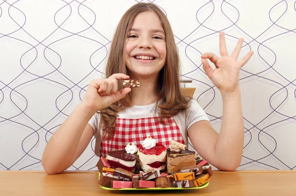 Šťastná holčička s sladké koláče a značka ok ruky — Stock fotografie