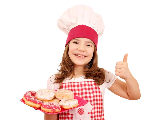 Šťastná holčička vařit s koblihy a palec — Stock fotografie