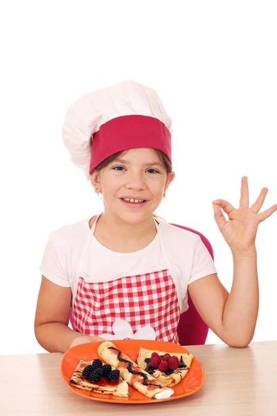 Ευτυχισμένη κοριτσάκι που μαγειρεύουν με κρέπες και εντάξει χέρι σημάδι — Φωτογραφία Αρχείου