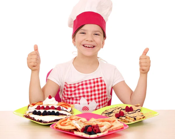 Heureux petite fille cuisinier avec crêpes et pouces vers le haut — Photo