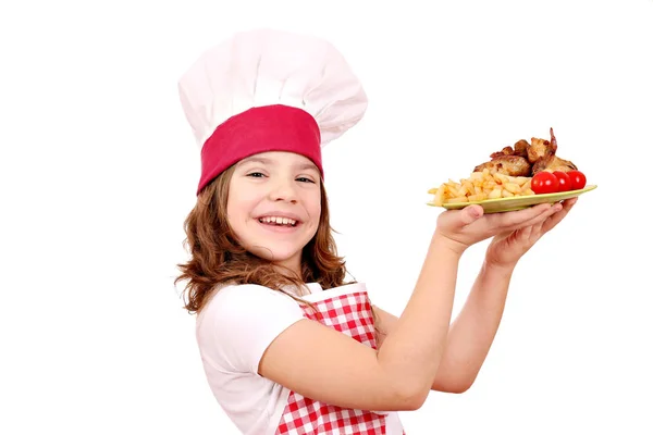 Happy little girl cook with roasted chicken wings on plate — Stock Photo, Image