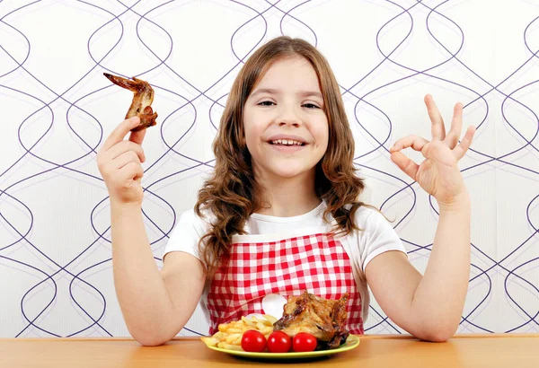 Lycklig liten flicka med rostade kycklingvingar och ok hand tecken — Stockfoto