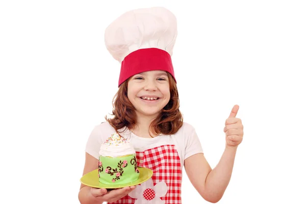 Heureuse petite fille cuisinier avec gâteau et pouce vers le haut — Photo