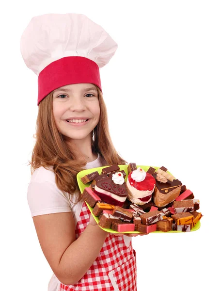 Feliz niña cocinera con pasteles dulces en el plato — Foto de Stock